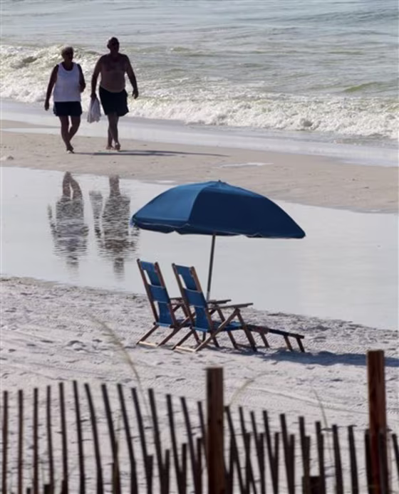 People walk past empty beach chairs in Destin, Fla., on Sunday.&nbsp;Some hotels and condominium owners along the Gulf say their business is down by 50 percent. 